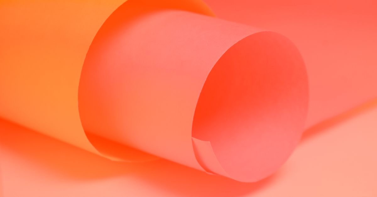 Home Close-up of rolled pink and orange paper creating a vibrant abstract background.